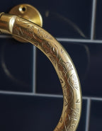 Decorative gold door handle on a dark tiled background