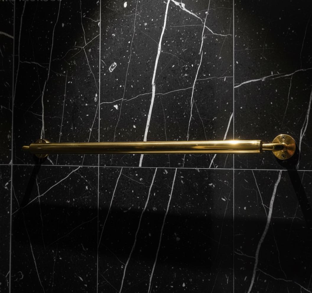 Gold towel bar on a black marble wall