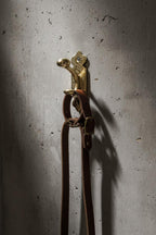 Brass fire tongs with decorative handle on a textured gray background