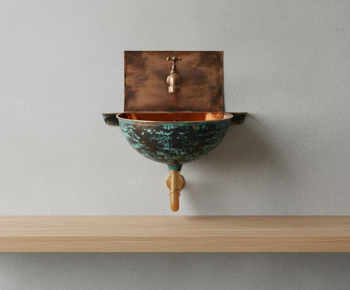 Copper wall-mounted sink with a rustic finish on a light gray wall.