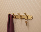 Gold wall hook with a purple cloth and keys on a beige wall.