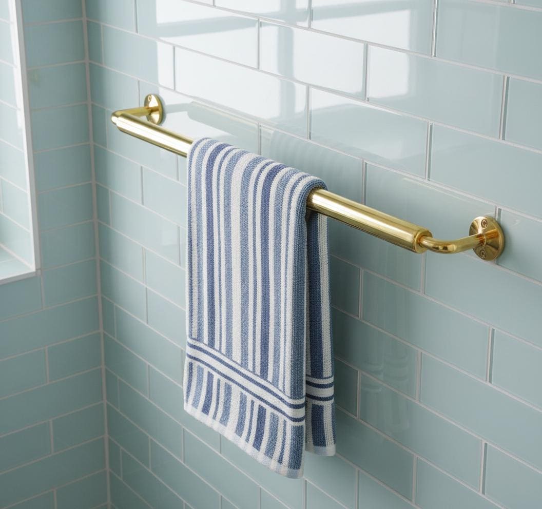 Gold towel rack with a blue and white striped towel on a tiled bathroom wall.