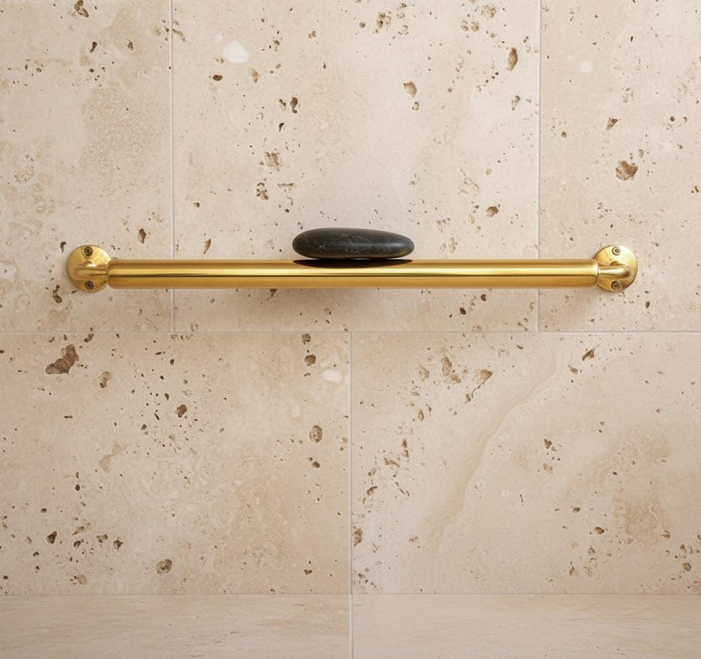 Gold grab bar mounted on a beige tiled wall