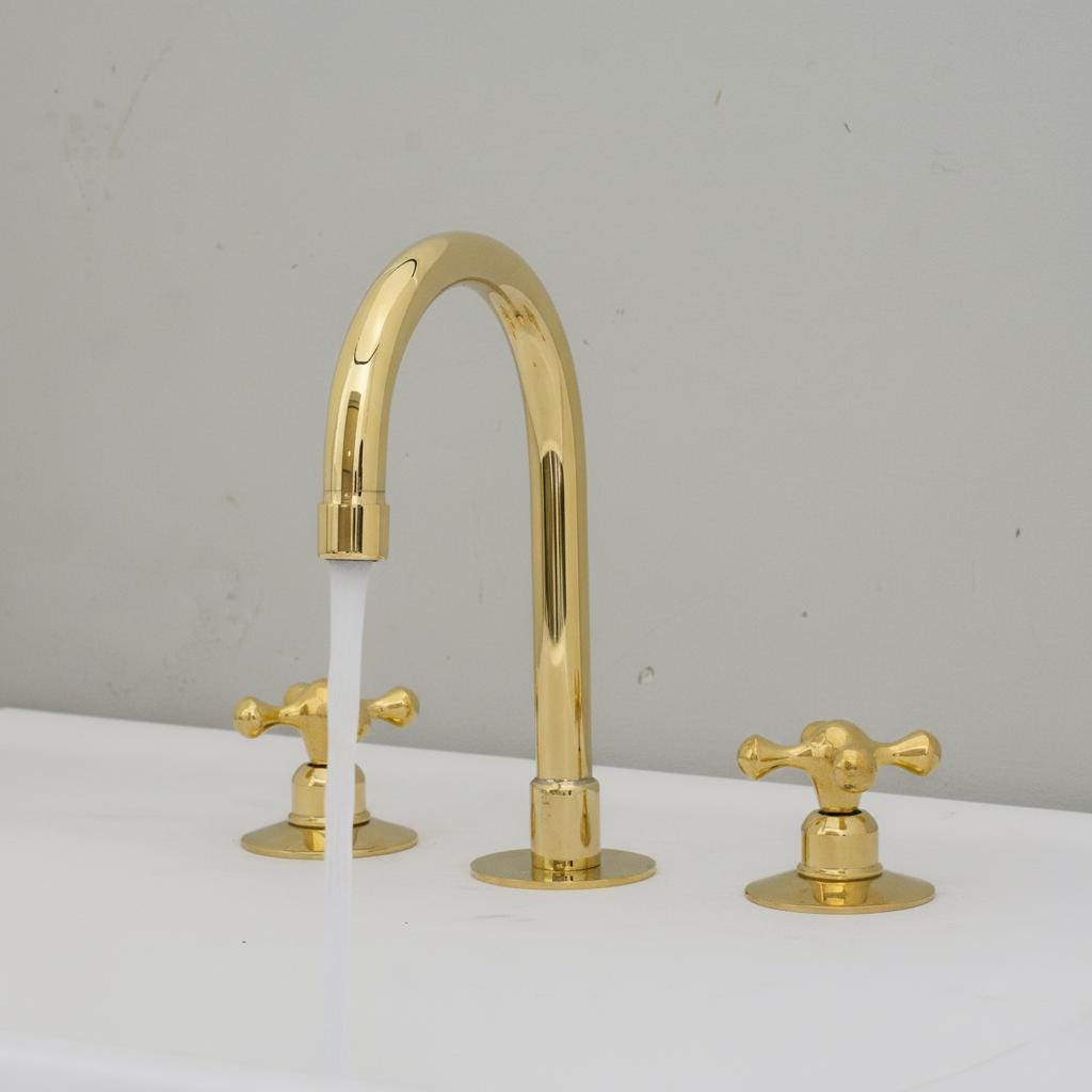Gold faucet with water flowing on a white surface and gray background