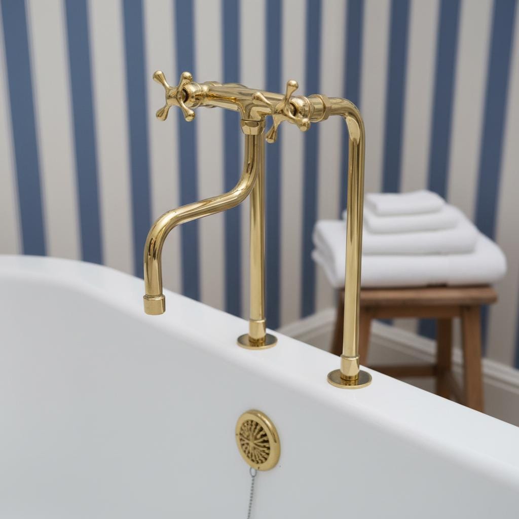 Gold faucet on a white sink with striped wallpaper in the background