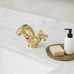Gold faucet on a marble countertop with soap and a soap dispenser.
