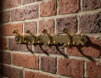 Gold wall hook with multiple hooks on a brick wall