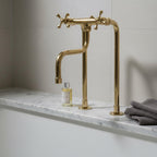 Gold faucet on a marble countertop with a bottle and towel in the background