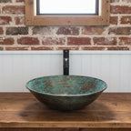 Decorative glass sink on a wooden countertop with a brick wall background