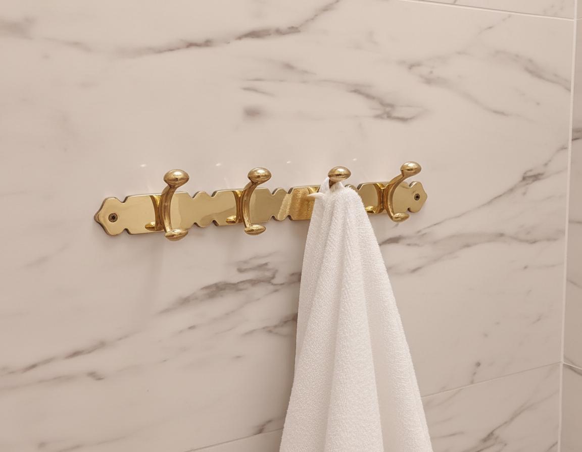 Gold towel rack with a white towel on a marble wall