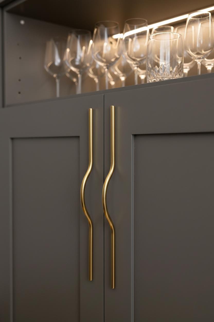 Dark gray cabinet with gold handles and wine glasses on a shelf above.