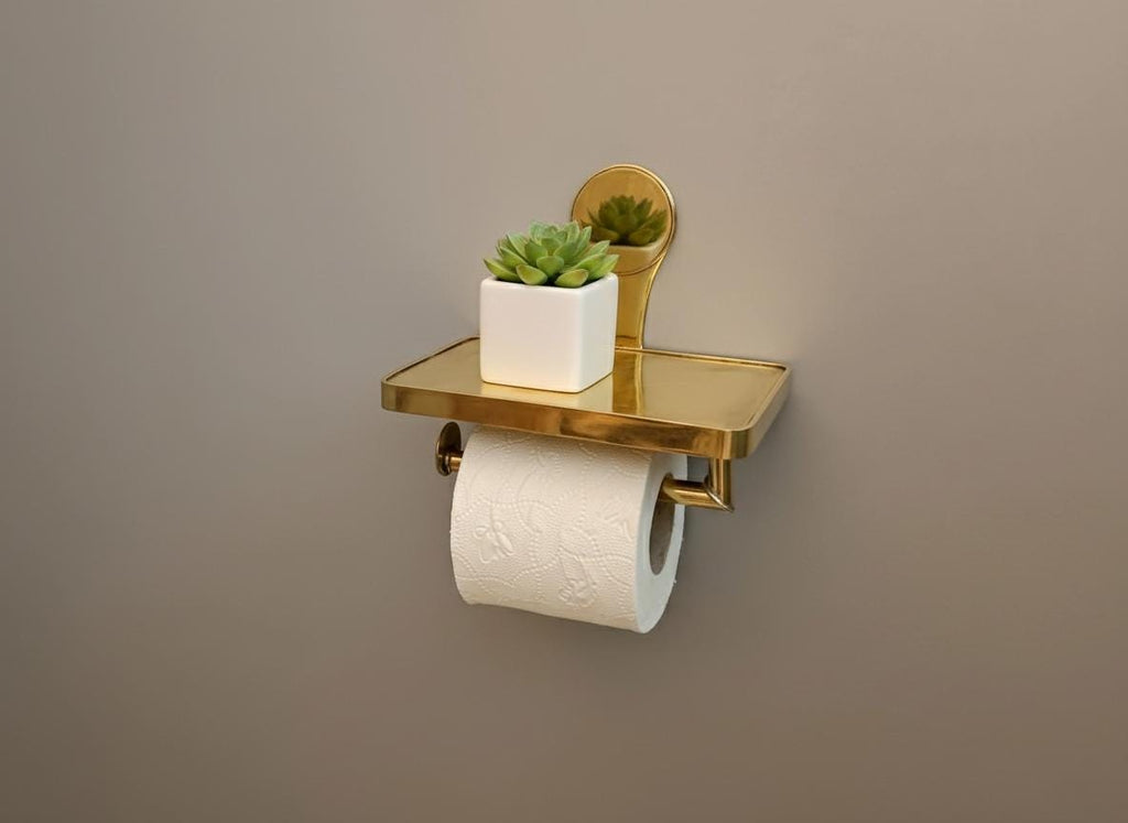 Gold toilet paper holder with a white roll and small potted plant on a brown background