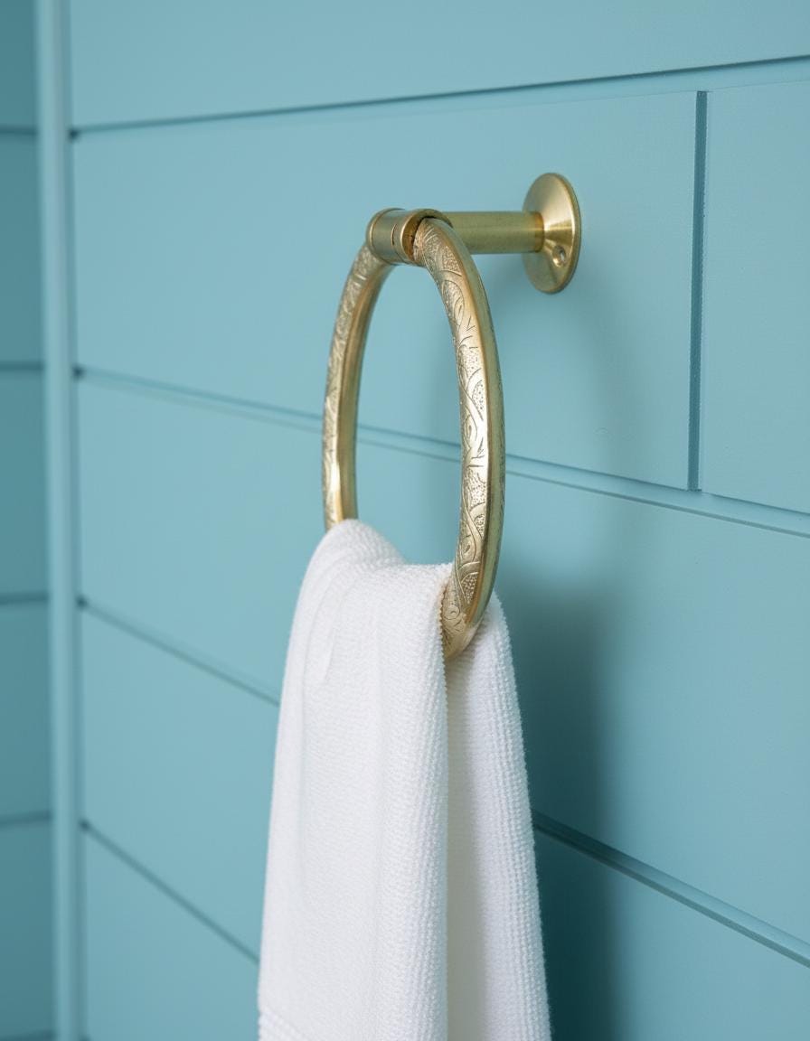 Gold towel ring with a white towel against a blue wall