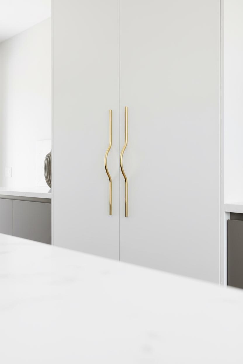 White wardrobe with gold handles in a minimalistic room.