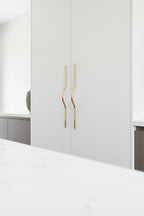 White wardrobe with gold handles in a minimalistic room.
