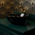 Black sink with gold faucet against a decorative wall