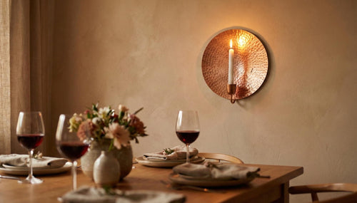 Dining table set with wine glasses, plates, and a vase of flowers, candlelit ambiance.