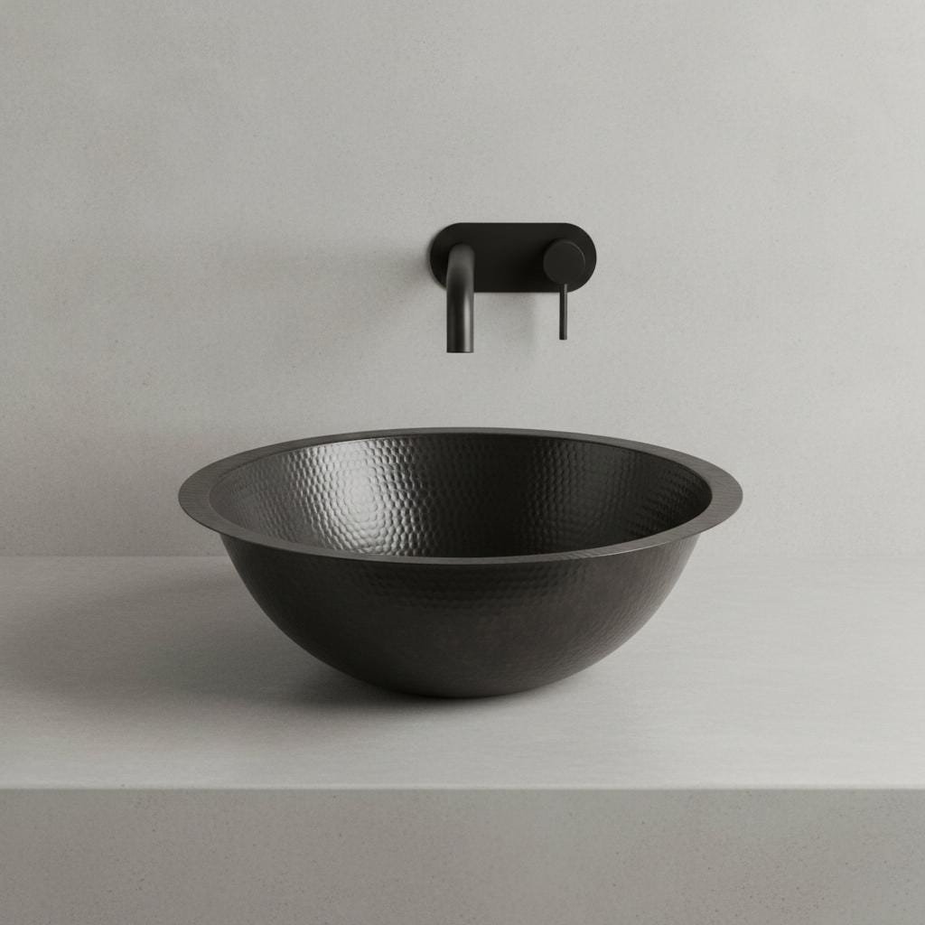 Black hammered metal sink with faucet on a light gray background