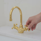 Gold faucet with a hand turning the handle on a white background