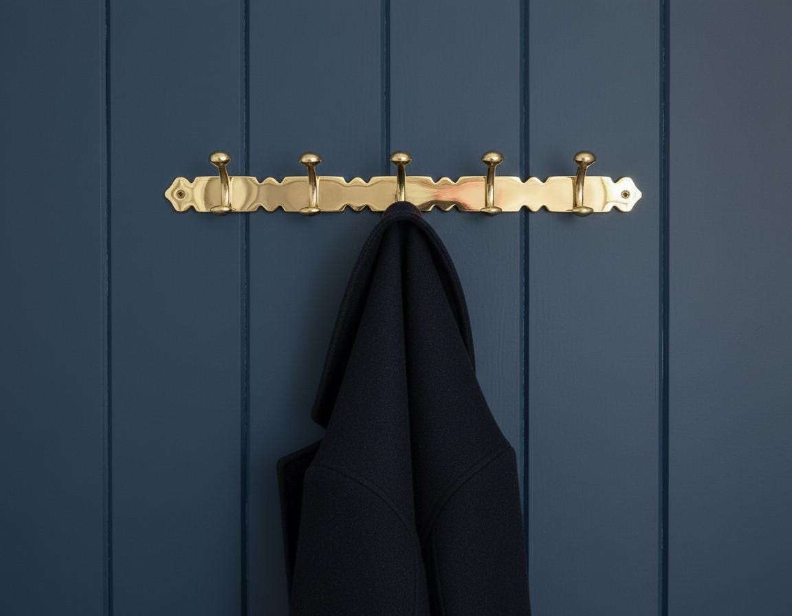 Gold hook with a black coat on a blue wooden panel background