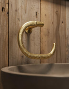 Decorative gold handle on a sink against a wooden background