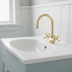 Bathroom sink with gold faucet against a white paneled wall