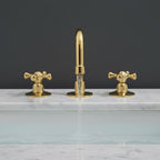 Gold faucet set on a marble countertop with a dark background