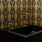 Black sink with gold faucet against a geometric patterned wall