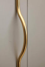 Gold curved handle on a light-colored cabinet door