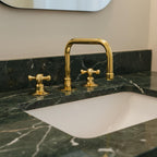 Gold faucet and handles on a marble countertop with a white sink.