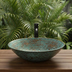 Turquoise mosaic sink on a wooden surface with green foliage in the background