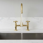 Gold kitchen faucet with water flowing on a marble countertop