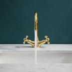 Gold faucet with water flowing on a marble surface against a dark teal wall