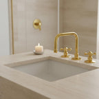 Bathroom sink with gold faucet and handles on a neutral background