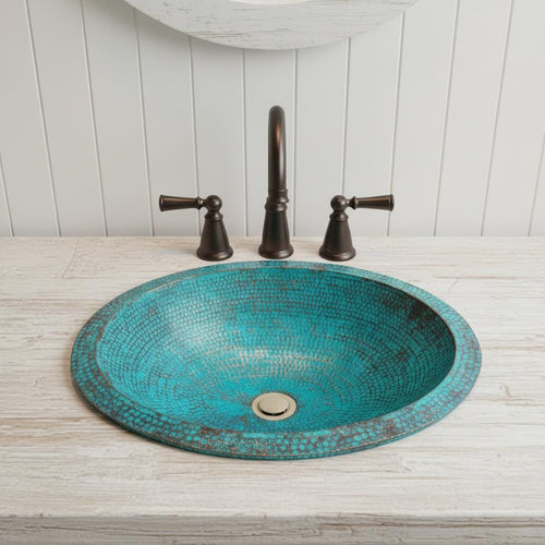 copper sink with bronze faucet and handles on a wooden countertop.