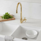 Kitchen sink with gold faucet and white bowl on a light-colored countertop.