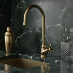 Gold faucet on a marble countertop with decorative bottles.