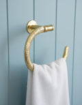 Gold towel hook with white towel on a blue wooden panel background