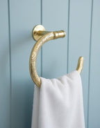 Gold towel hook with white towel on a blue wooden panel background