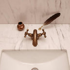 Decorative bronze faucet with a feather on a marble countertop