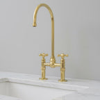 Gold kitchen faucet on a marble countertop with a light gray wall background