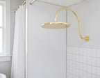 Unlacquered solid brass gooseneck shower arm with round rainfall showerhead for a luxurious bathroom finish