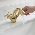 Gold faucet with water flowing into a sink on a marble countertop