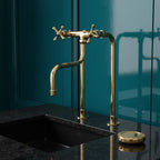 Gold faucet on a black sink against a teal wall