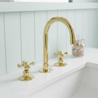 Gold faucet and handles on a white sink with a light blue wall in the background