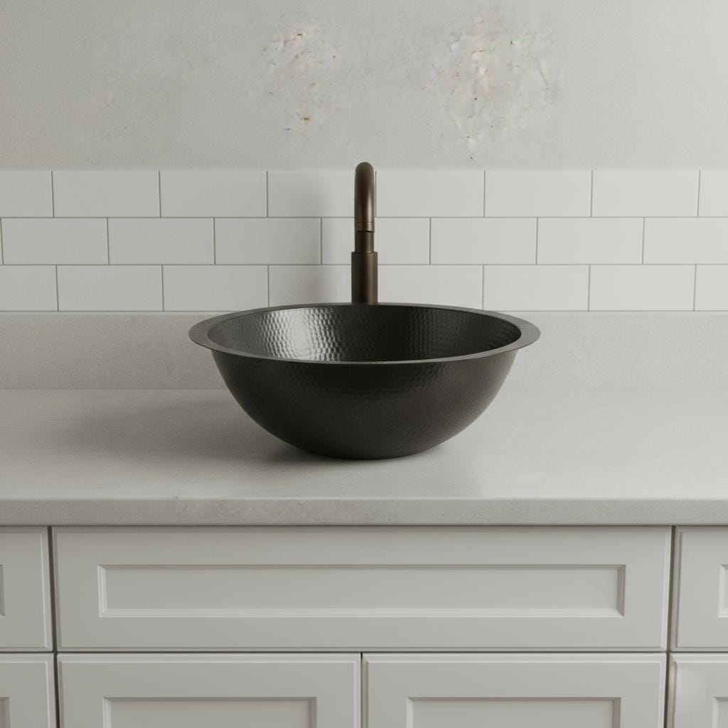 Black sink on a light gray countertop with a white tiled wall background