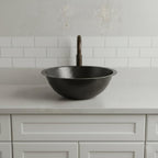 Black sink on a light gray countertop with a white tiled wall background