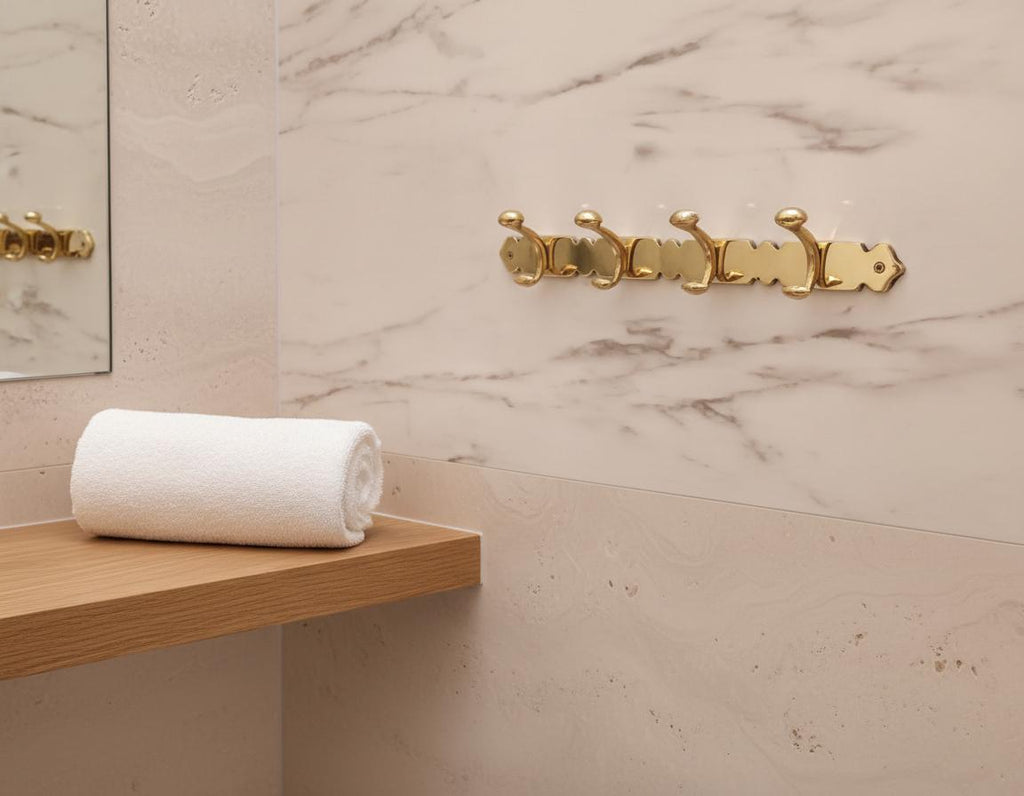 White towel on a wooden shelf with gold hooks against a marble wall.