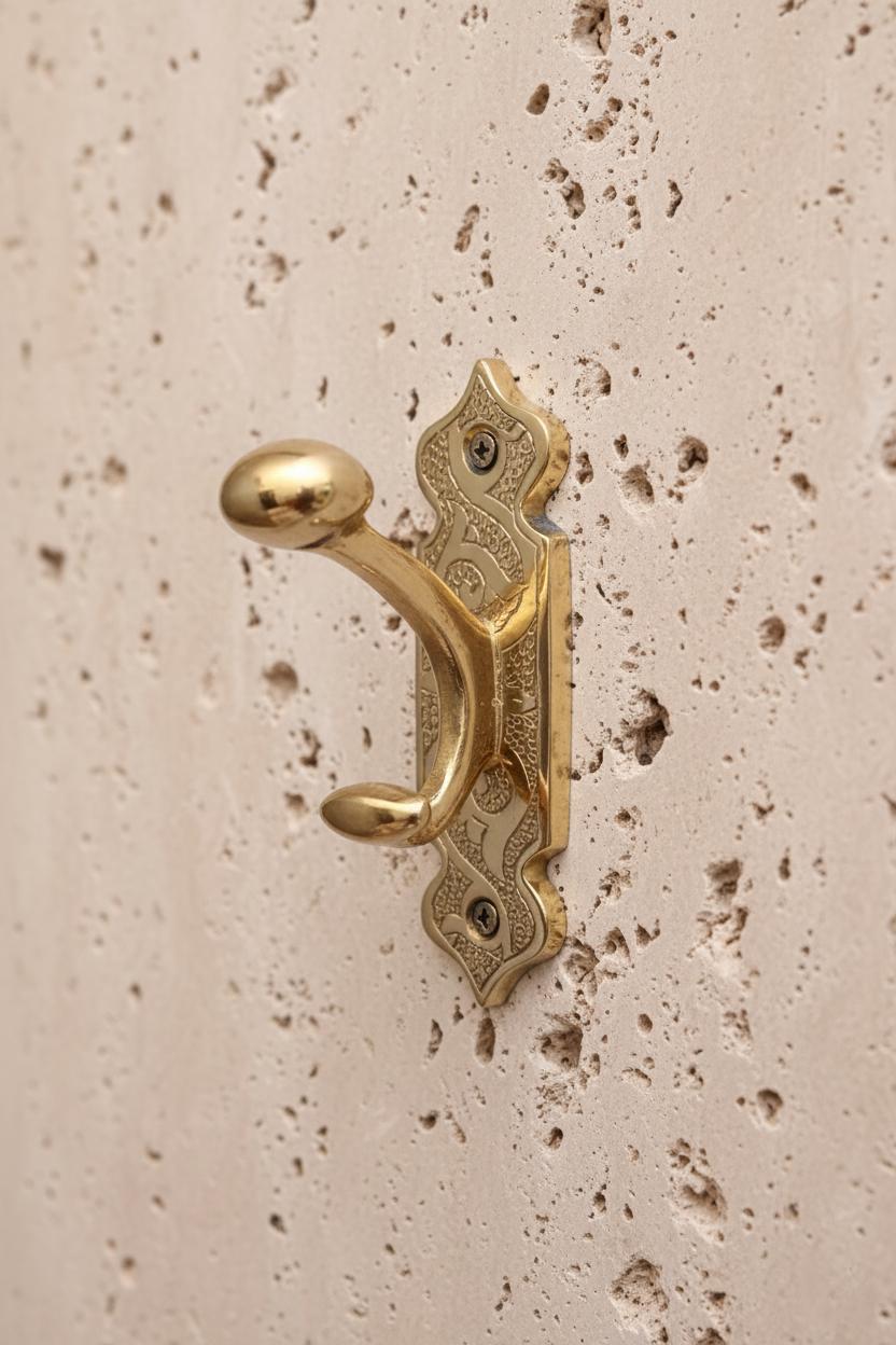 Decorative gold door handle on a textured beige wall