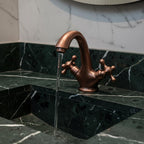 Bronze faucet on a marble sink with water flowing